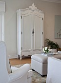 Antique, white-painted wooden wardrobe with carved pediment in lounge area