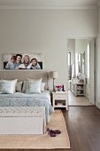 Bedroom in natural shades with picture of family and open door leading to ensuite bathroom