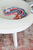 Necklaces of different colours in white dish on coffee table