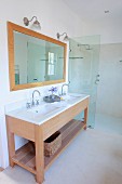Waschtisch mit zwei Unterbaubecken und gerahmter Spiegel an Wand, seitlich bodenebener Duschbereich mit Glas Trennscheibe in modernem Bad