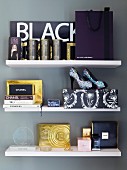 Various perfumes and ladies' accessories on white floating shelves