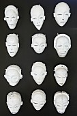 Various white theatre masks hung on black wall