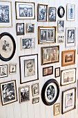 Gallery of retro-style family photos in various frames on white wooden wall