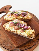 Slices of bread topped with egg salad, herring and red onions