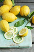 Sorrento lemons with leaves, whole and sliced, on a chopping board