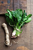 Fresh spinach leaves tied with kitchen twine on a wooden surface