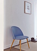 Blue, fifties chair against white wall in simple, white hallway