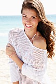 A young woman in a summer jumper on a beach