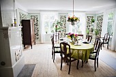 Esszimmer mit dunklen Holzstühlen um Tisch, an Wand schmale Paneele mit Pflanzendarstellung in ländlicher Ambiente