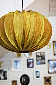 Pendant lamp with gold fabric lampshade; gallery of photos in blurred background