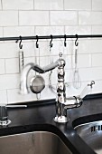 Retro tap fittings on undermount sink and kitchen utensils hanging from metal rail