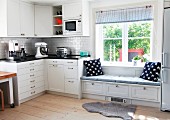 Corner unit in Swedish, country-house kitchen with blue and white accessories on integrated window seat