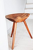 Three-legged wooden stool with ergonomic seat