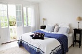 Double bed with blue and white patterned bed cover and dark wood bedside cabinet in bedroom