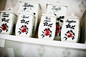 China spice boxes with rose motif on shelf