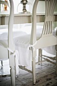 White-painted wooden chairs seat covers over seat cushions