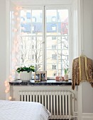 Sprossenfenster mit weisser Lampiongirlande und goldfarbene aufgehängte Paillettenjacke in städtischem Landhaus-Schlafzimmer