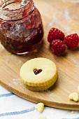 Homemade Jammie Dodgers and raspberry jam on a floured wooden board