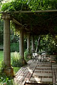 Charming seating area under climber-covered pergola with antique stone pillars