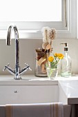 Sink with mixer tap and washing-up brushes in glass container