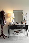 Plexiglas chair at antique, dark-wood dressing table with table lamp with pale lampshade