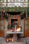 Weihnachtlich geschmücktes Haus und Terrasse mit antikem Steintisch und Bodenlaternen