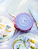 Unbaked pizzas topped with pears, blue cheese and red onions