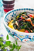 A bowl of polenta with a chard and tomato medley and pine nuts