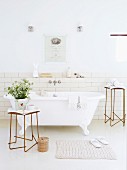 Free-standing vintage bathtub and delicate metal side tables in front of walls with white subway tiles