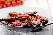 Mussels with tomato sauce on a black plate