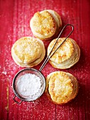 Mince pies and a sieve of icing sugar on a red wooden surface