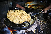 Omapodi aus dem heißen Öl heben (Kichererbsen- und Reismehl Snack, Indien)