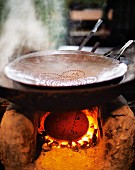 A steaming pan of oil on a traditional clay stove