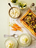 An arrangement of raw vegetables, a dip, courgette tart and lemon cream