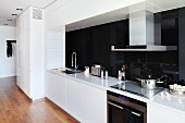 Cool, white fitted kitchen with black glass splashback