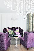 Purple upholstered furniture with the crystals on a chandelier in thr foreground