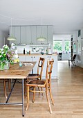 Improvisierter Tisch auf Klassiker Metallgestell (Egon Eiermann) und alte Holzstühle vor offener Küche in grosszügigem Wohnraum