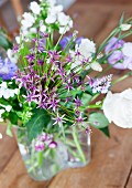 Bouquet of white & purple garden flowers in glass vase