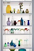 Glasses and vases of various colours and styles on modern shelves