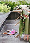 Colourful fabric slippers next to lounger with blanket on stone-flagged terrace