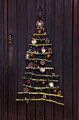Stylised Christmas tree made from mossy branches with natural decorations and straw stars hanging on front door