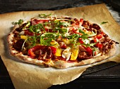 Hausgemachte Pizza mit Paprika, Peperoniwurst und Rucola