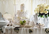 Festlicher Hochzeitstisch mit weißem Rosenstrauss und kunstvoller Hochzeitstorte