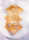 Three folded crepes dusted with icing sugar