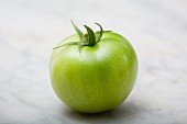 A green tomato on a marble platter