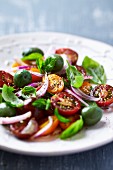 Cherry tomato salad with green olives and fresh herbs (close-up)