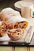 Apple strudel with raisins and icing sugar, sliced