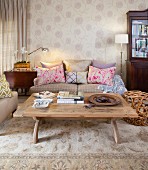 Comfortable, beige living room with modern standard lamp, patterned wallpaper and scatter cushions providing accents of colour