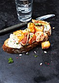 A slice of bread topped with salmon, cream cheese, figs and herbs