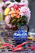 Jug of autumnal flowers on metal table